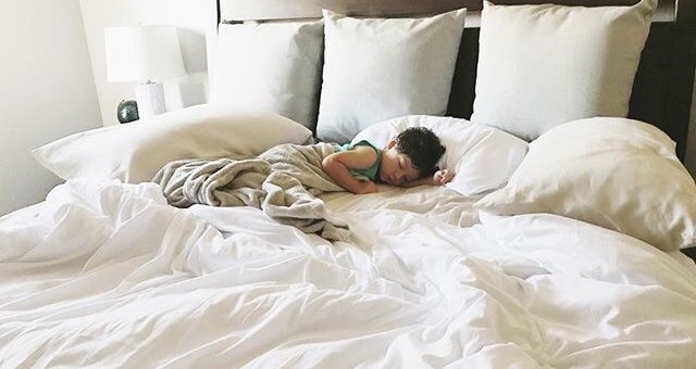 孩子睡在铺着白色床单的床上